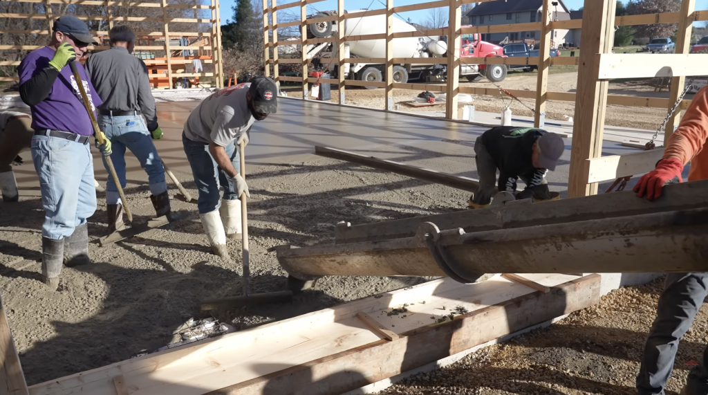 Concrete is poured at the garage door opening to form a recessed trough detail, allowing wind-driven rain or snowmelt to drain away instead of entering the shop.